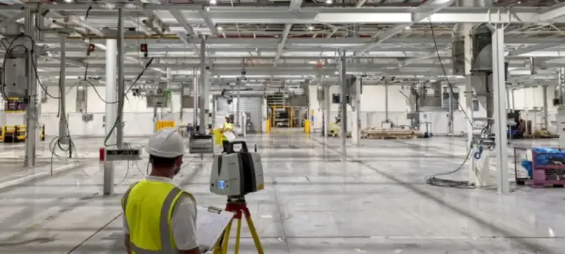 Site survey measuring floor level and overhead clearance in an empty factory hall