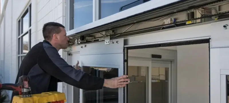 Technician servicing the operator and track of an automatic sliding door